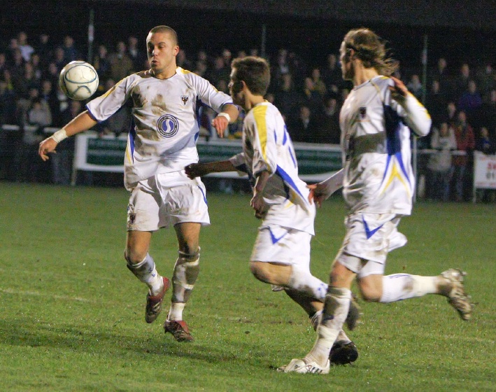 Three AFC Wimbledon players chase the ball ...
