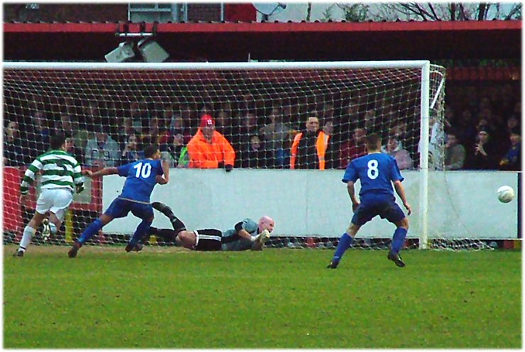 Wastell saves but McDowall and Gell are unable to get to the ball
