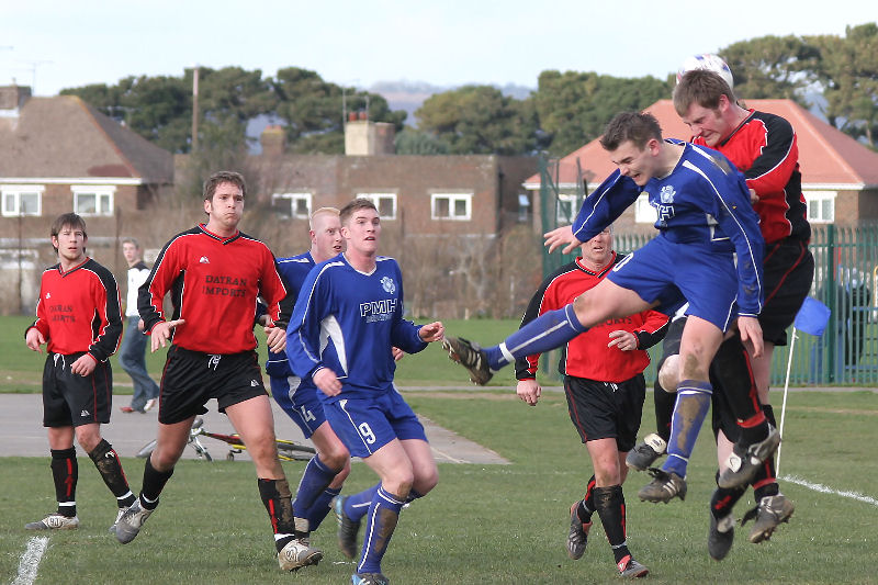 Goalkeeper John Sutton (hidden) punches away from Craig Cox and a Wadhurst defender
