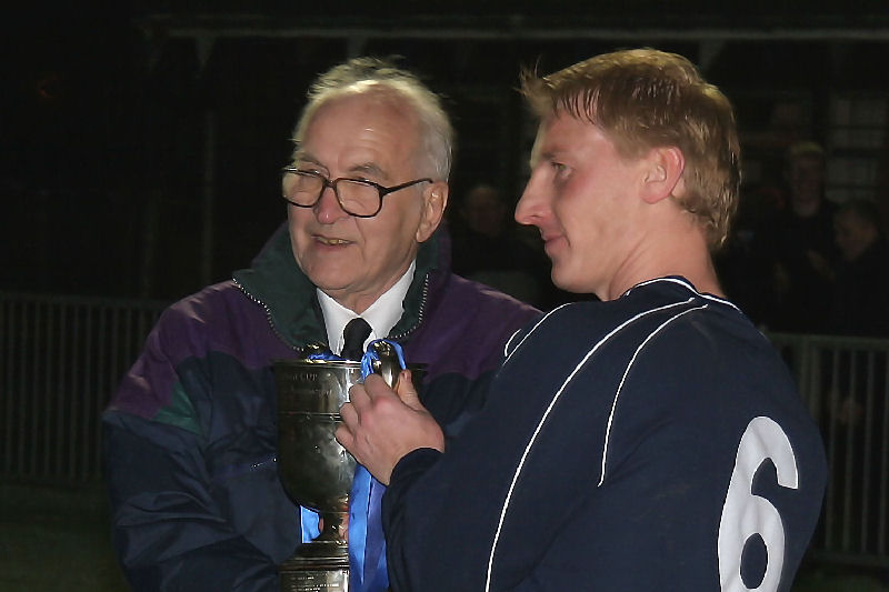 Wealden captain Justin Harris is presented with the cup by Peter Strange, the President of the SCFL
