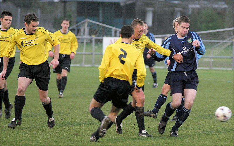 Gavin Jones on the ball with Gary Young and Darren Akmenkalns close by
