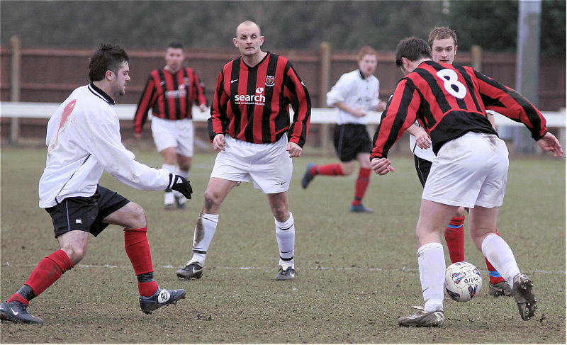 Phil Marsh on the ball with Rob Wimble and Doug Peach close by
