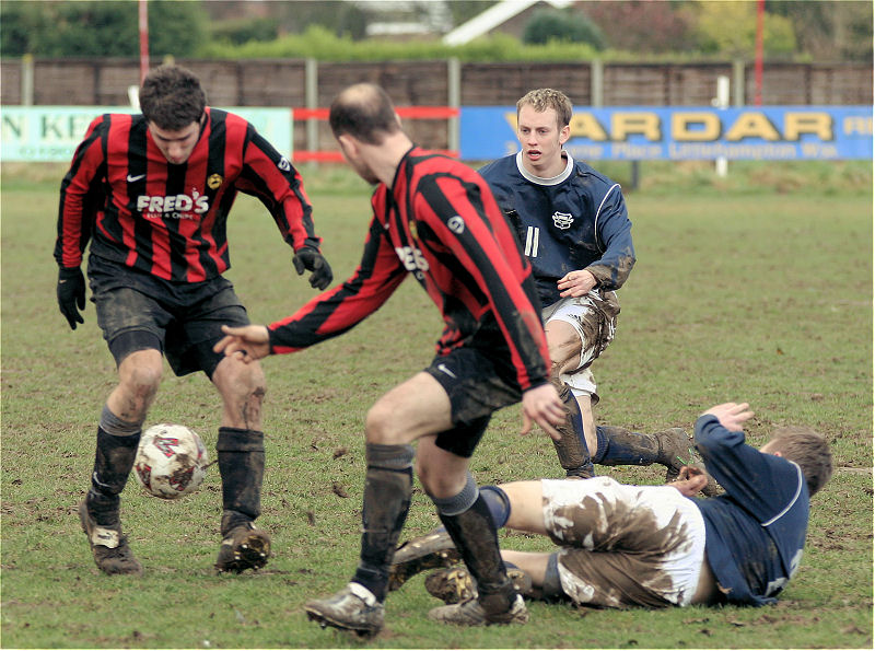 Lee Barnard slides in to nip the ball away from Tom Manton and Darren Annis with Mike Huckett close up
