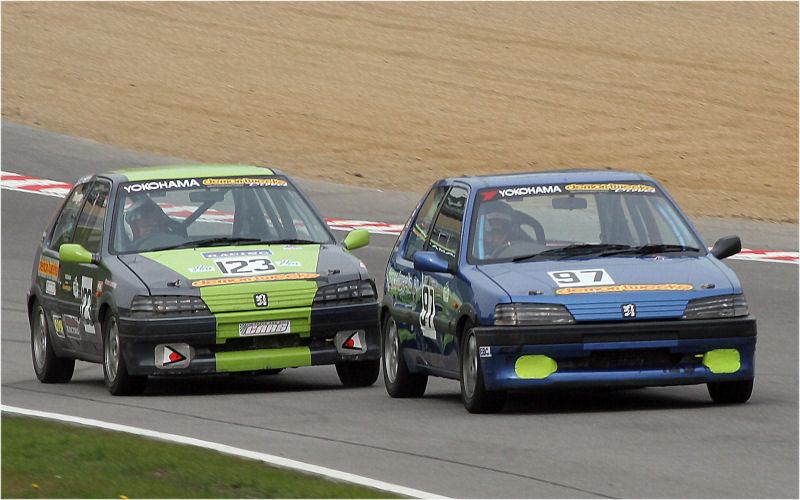 The Peugeot 106 Si s of Damian Cottrell (97) and Andrew Thorpe (123) race up to the hairpin
