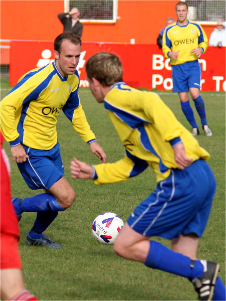 With Gary Brockwell on the ball, Brad Manton starts a run watched by Greg Manton
