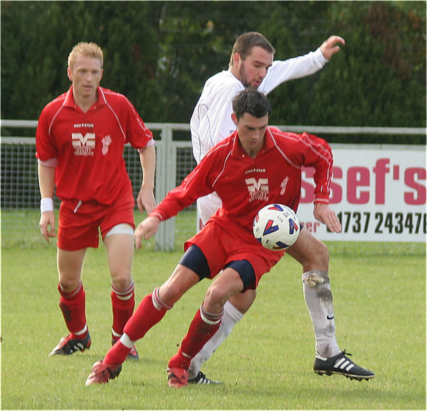 Danny Guscott shields the ball from Chris Morrow watched by Stuart Channon
