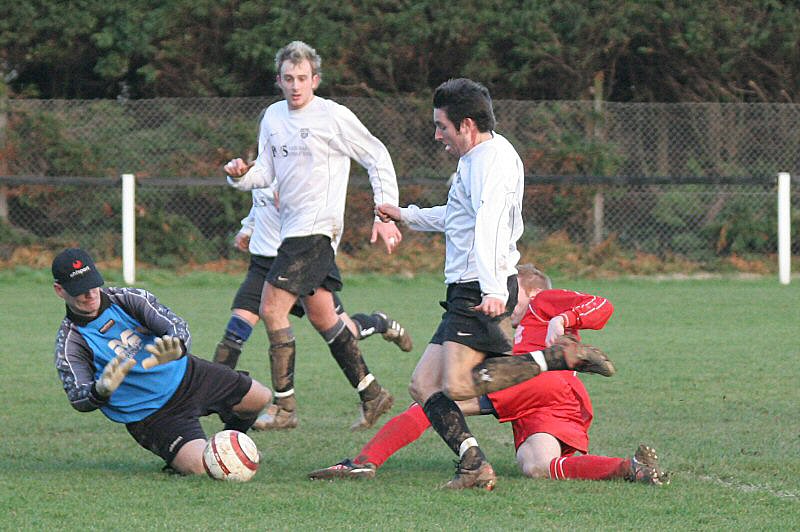 Keeper Chris Roberts blocks the ball with Chris Hibberd running in...
