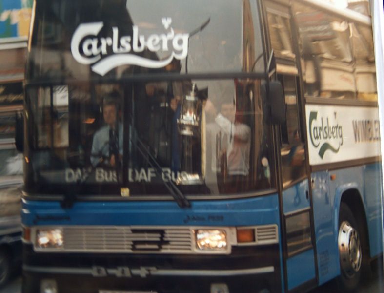 The team coach comes up behind the supporters bus and Bobby Gould shows off the FA Cup
